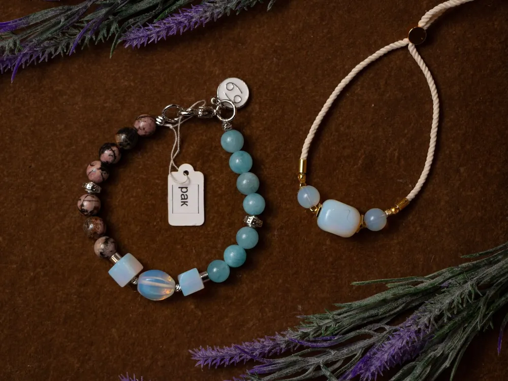 Pulseiras de pedras naturais sobre mesa de madeira, com ramos de lavanda ao lado